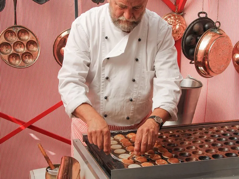 Koch bereitet kleine Pfannkuchen live an der Cooking-Station zu Koch bereitet kleine Pfannkuchen live an der Cooking-Station zu